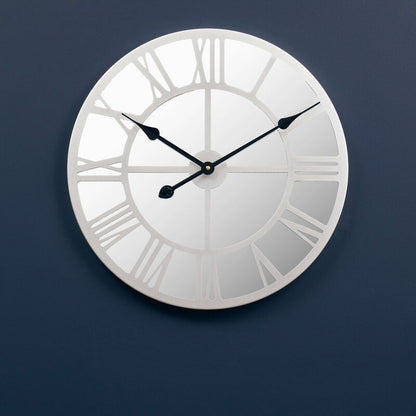 Silver wall clock with Roman numerals on a dark blue wall