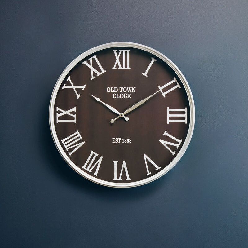 Wall clock with Roman numeral design on a dark blue wall
