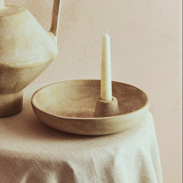 Ceramic pitcher and bowl with candle on a neutral background