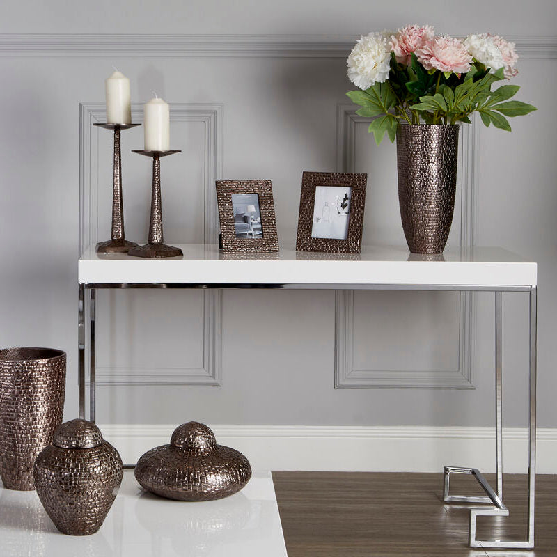 Decorative vases and candles on a table against a gray wall.
