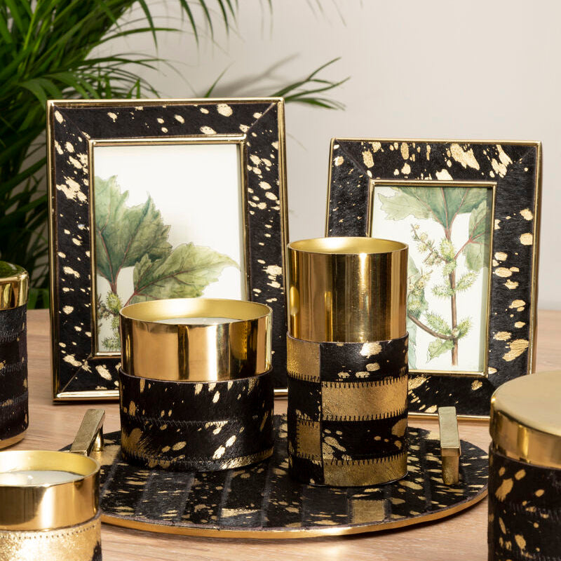 Decorative candles with black and gold marbled design on a wooden surface.
