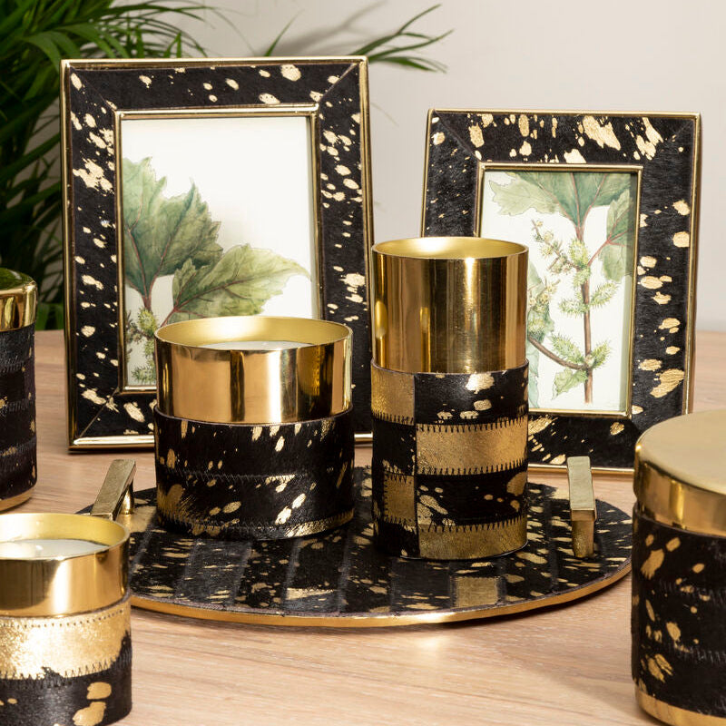 Decorative candles with black and gold marbled design on a wooden surface.