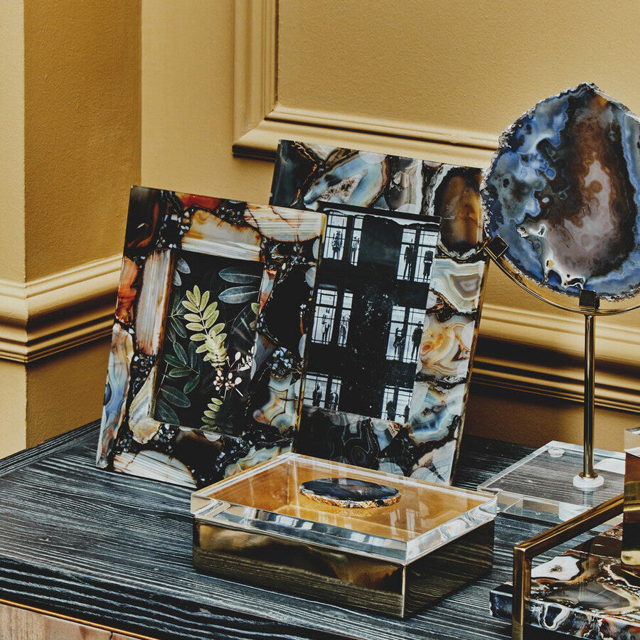 Decorative items including a small mirror with a textured surface on a wooden surface.