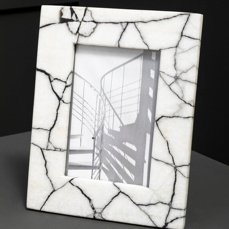 White marble effect photo frame with a black and white photo inside on a dark background