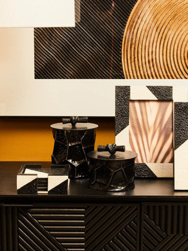 Decorative items on a shelf with geometric wall art in the background