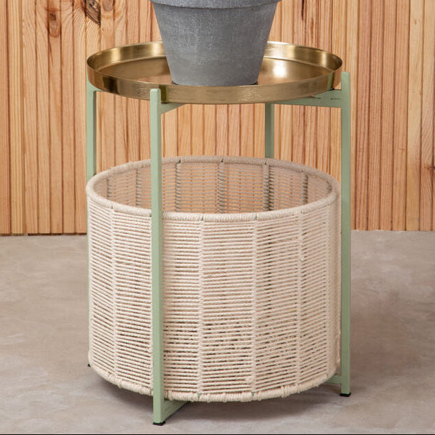 Small round table with a plant on top against a wooden wall.