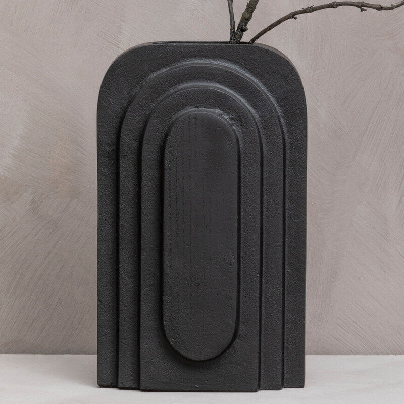 Black vase with a branch on a beige background
