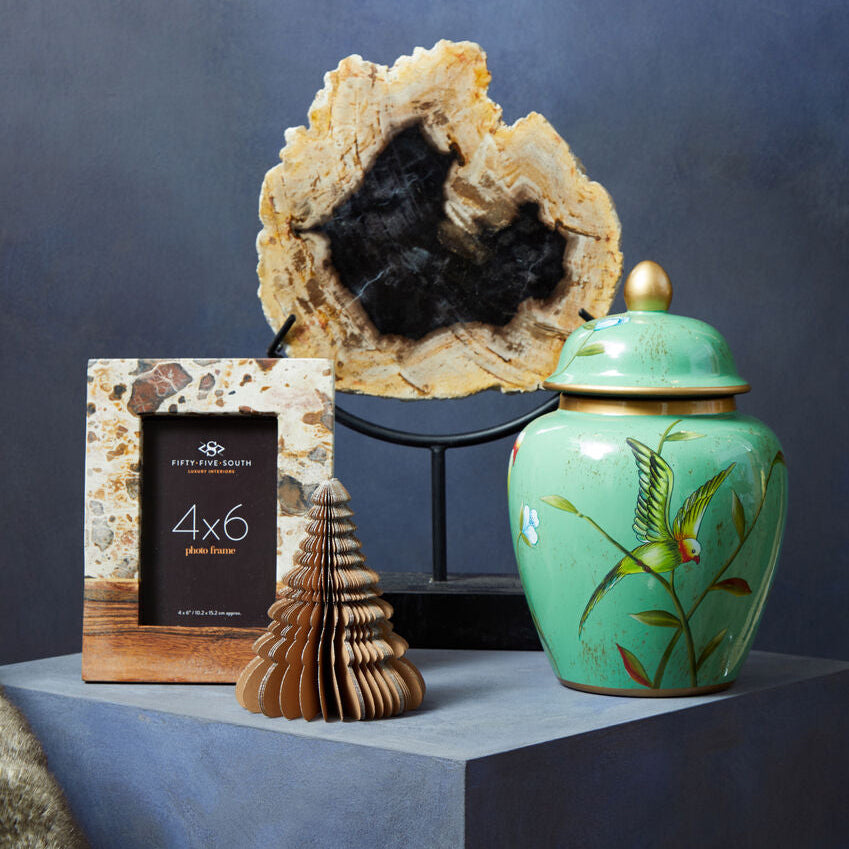 Decorative items including a photo frame, geode, and green ceramic jar on a blue surface with a dark background.