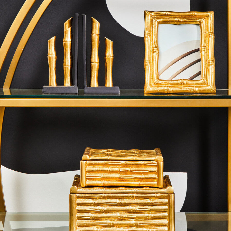 Decorative gold and black bookends and frame on a shelf against a black background