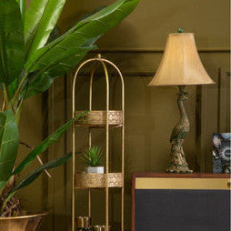 Decorative gold shelf with plants and a lamp in a room setting.