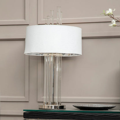 Modern lamp with a white shade on a glass table against a neutral wall.