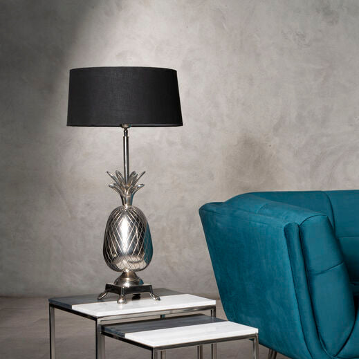 Modern living room setup with a blue sofa, glass coffee table, and decorative lamp against a textured wall.