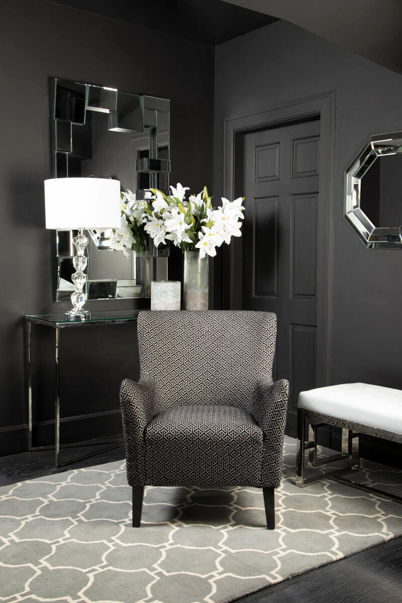Modern interior with a gray armchair, patterned rug, and decorative elements.