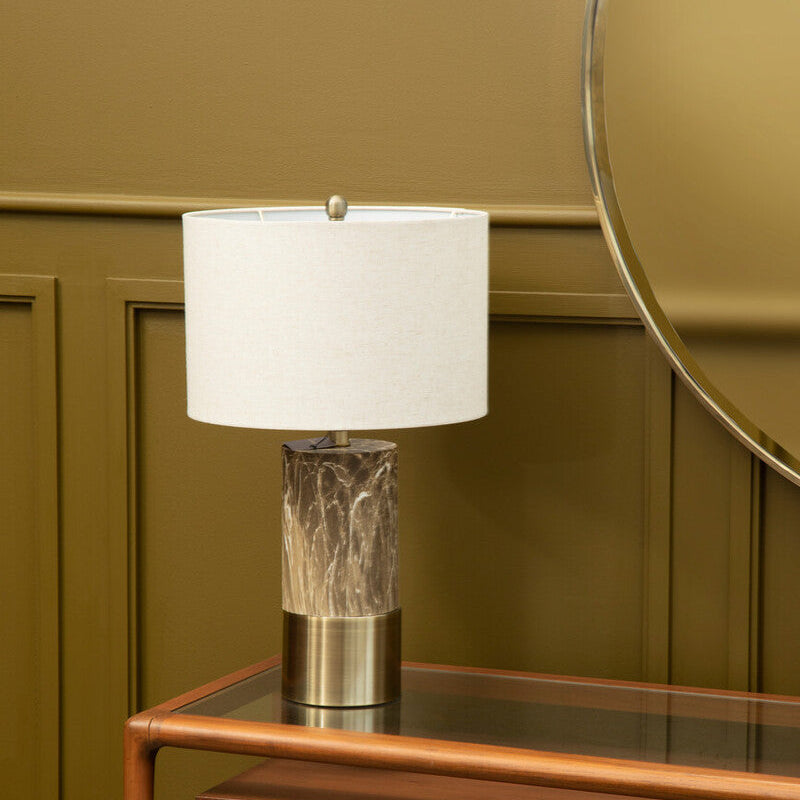Table lamp with a textured base on a wooden side table against a green wall.