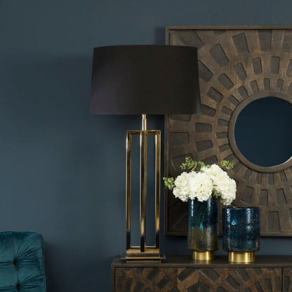 Decorative interior setting with a teal chair, lamp, and patterned cabinet against a dark wall.