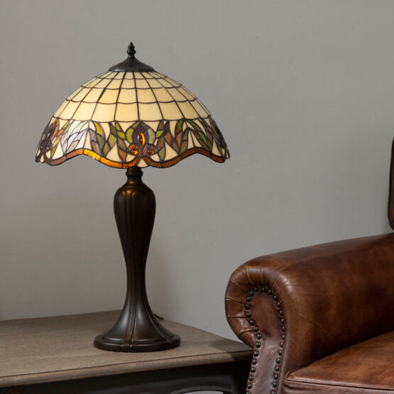 Brown leather armchair next to a table with a decorative lamp against a gray wall.