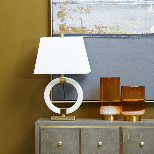 Gray dresser with gold accents against a gold wall with abstract art above.