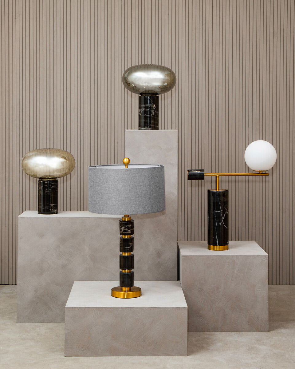 Modern table lamps with marble bases on concrete plinths against a striped wall.