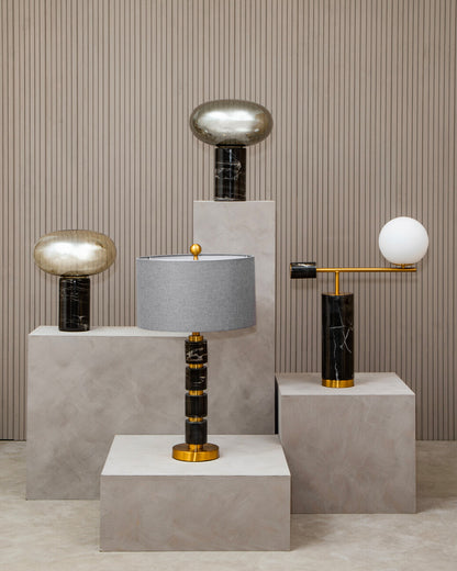 Modern table lamps with marble bases on concrete plinths against a striped wall.