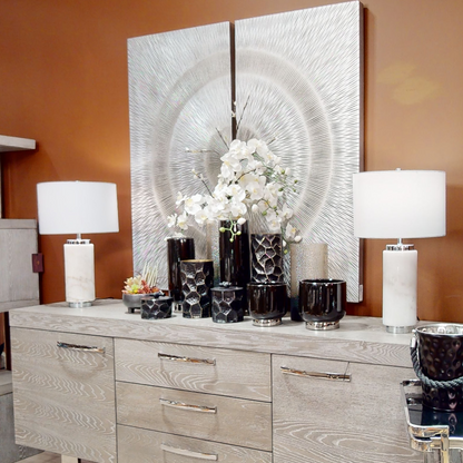 Decorative sideboard with large wall art, lamps, and flowers against a brown wall.