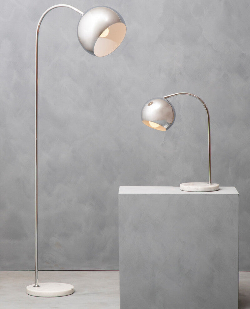 Two modern floor lamps with curved necks on a gray surface against a gray wall.