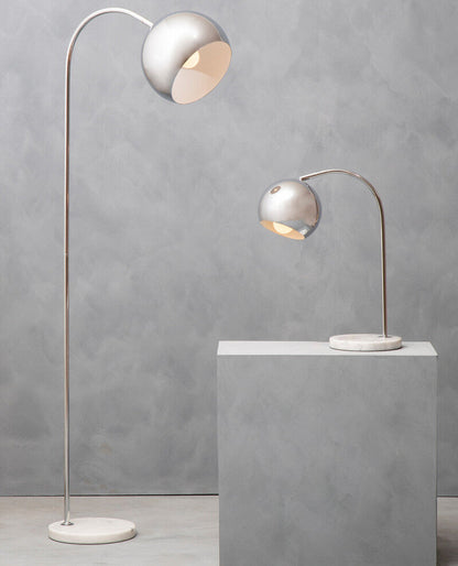Two modern floor lamps with curved necks on a gray surface against a gray wall.