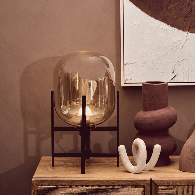 Decorative setting with vases, a lamp, and a framed abstract painting on a wall.