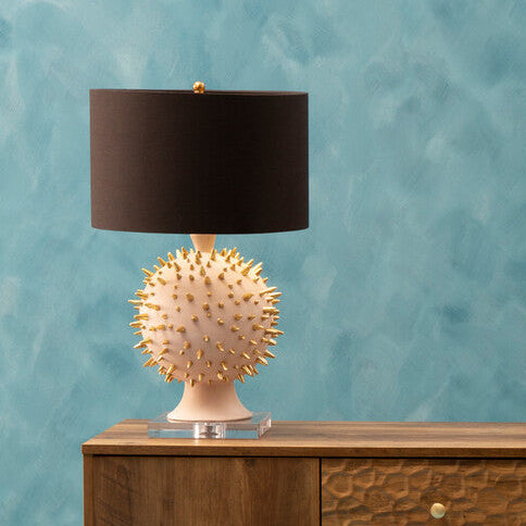 Wooden sideboard with decorative lamp and vases against a textured blue wall.