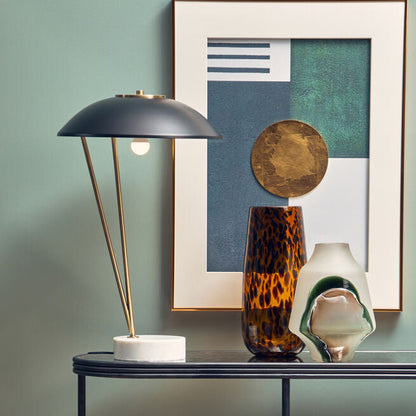 Console table with decorative items against a wall with a framed abstract painting.