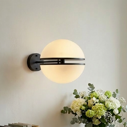 Wall-mounted light fixture with a vase of flowers and books on a wooden surface.