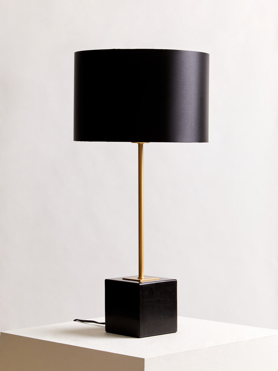 Black table lamp with a gold base on a white surface