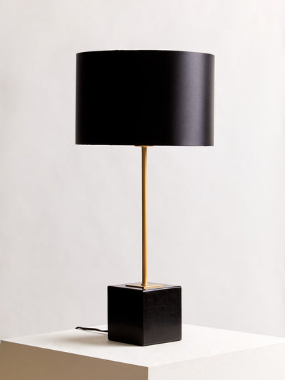 Black table lamp with a gold base on a white surface