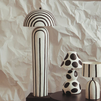Decorative vases and a lamp with black and white patterns on a textured white background