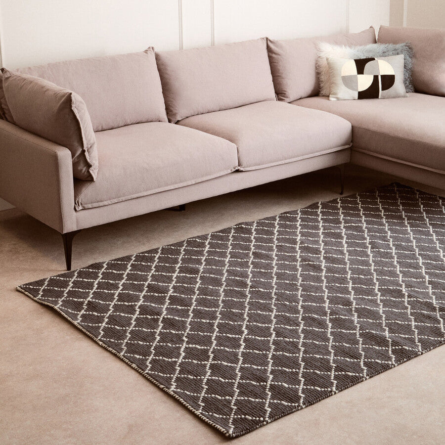Gray sectional sofa with a patterned rug in a living room setting
