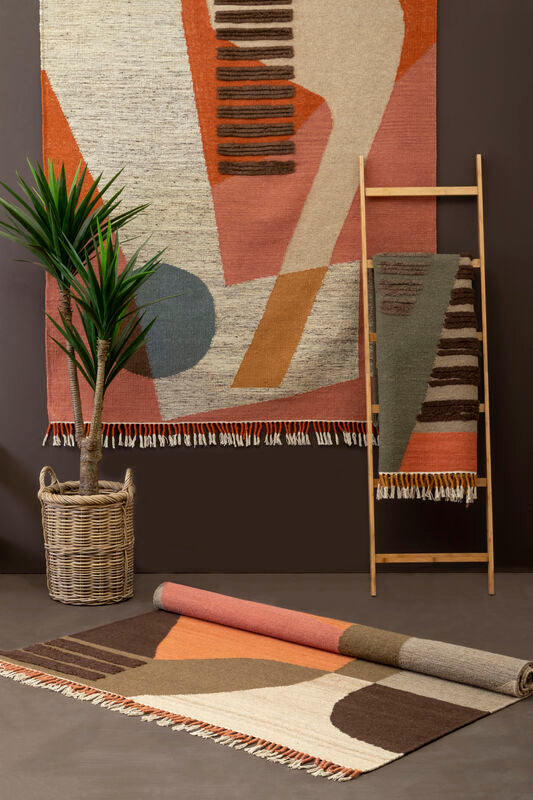 Geometric patterned rug with a plant and ladder against a dark wall.