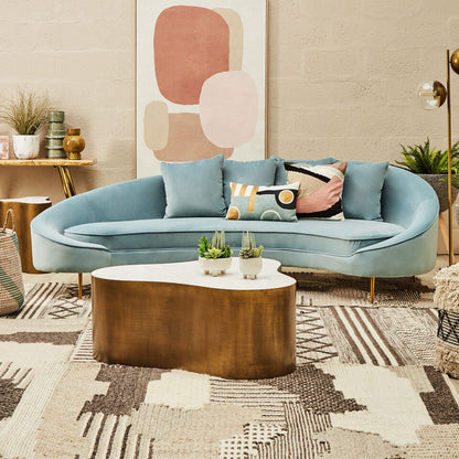 Modern living room with a curved light blue sofa, abstract art, and decorative items.