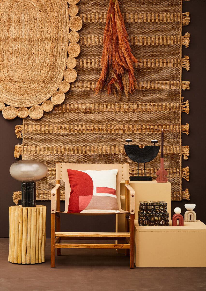 Decorative interior setting with a chair, cushions, and various decorative items against a textured wall.