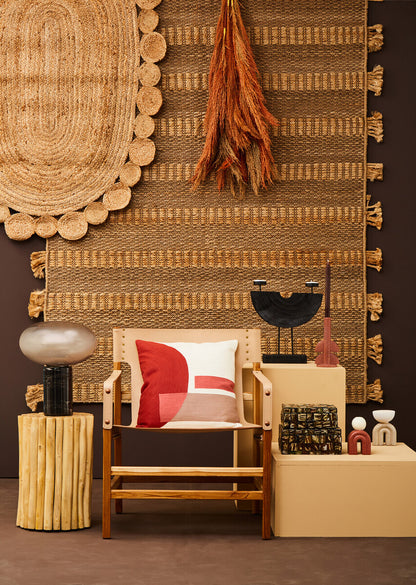 Decorative interior setting with a chair, cushions, and various decorative items against a textured wall.