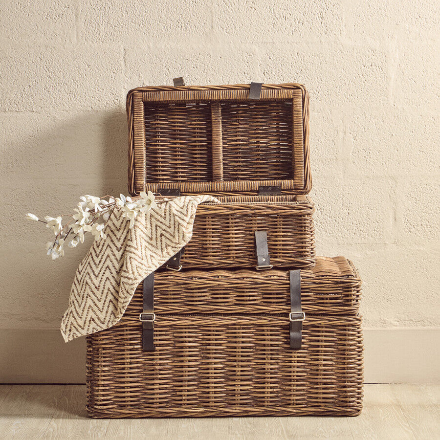 Two wicker storage baskets with a blanket and branch on a beige background