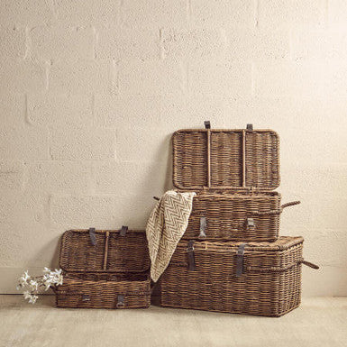 Set of wicker storage baskets with a blanket on a neutral background