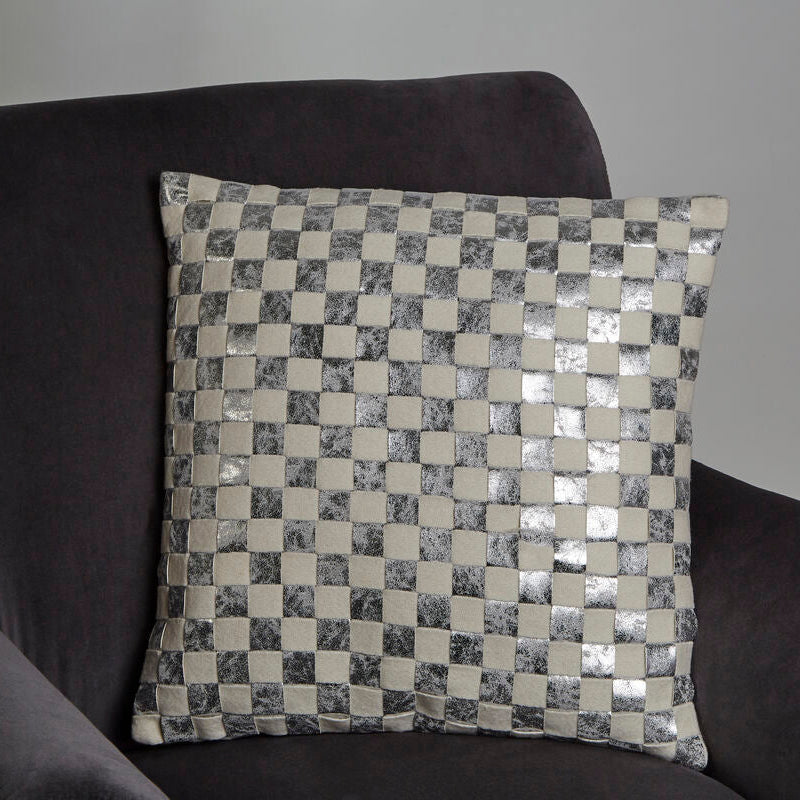 Decorative pillow with a checkered pattern on a dark sofa against a plain background