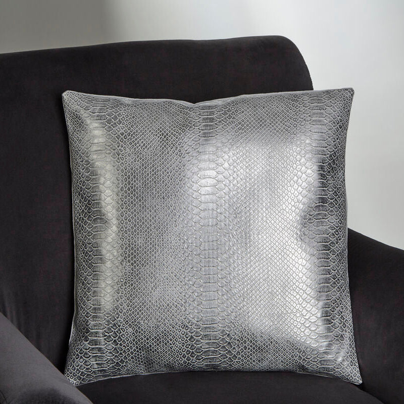 Silver textured pillow on a dark gray sofa against a plain background