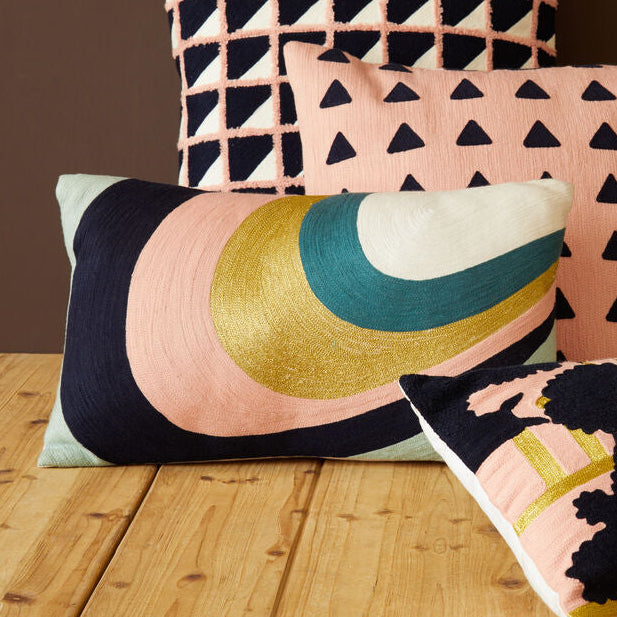 Four decorative pillows with geometric and floral patterns on a wooden surface.