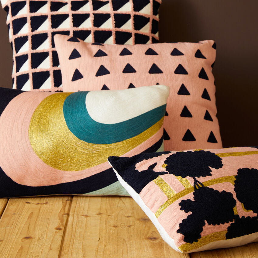 Four decorative pillows with geometric and abstract patterns on a wooden surface.
