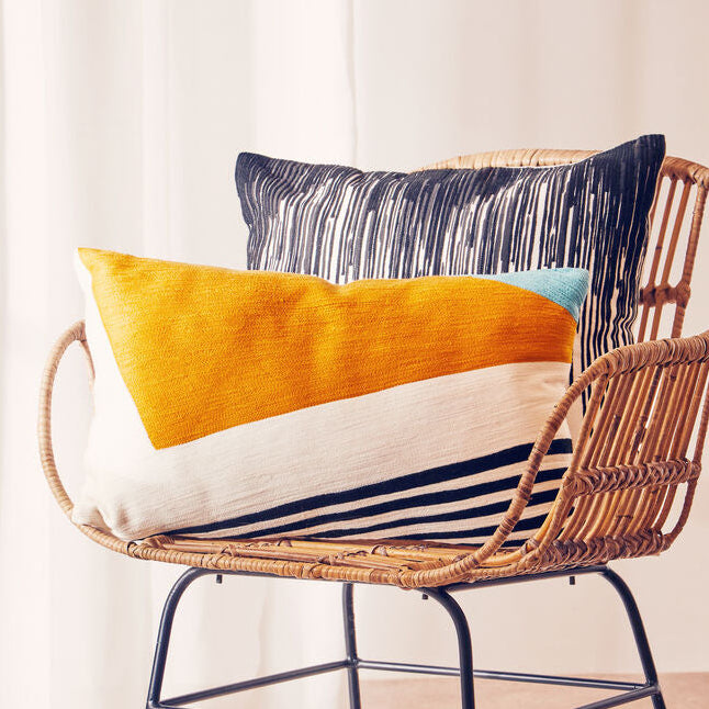 Wicker chair with colorful cushions in a room with white curtains