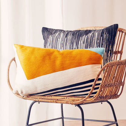Wicker chair with colorful cushions in a room with white curtains