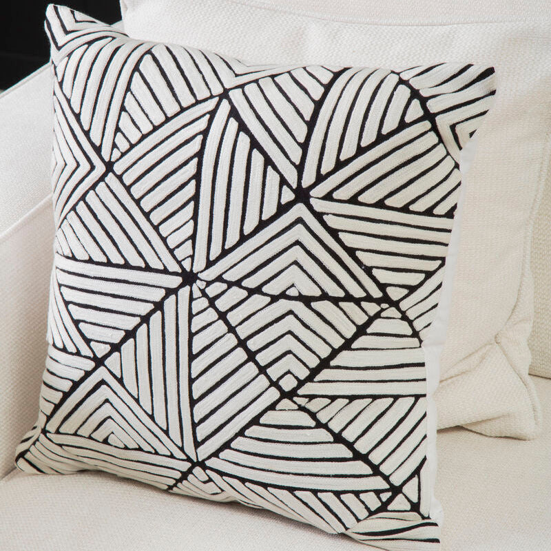Decorative pillow with black geometric pattern on a white couch