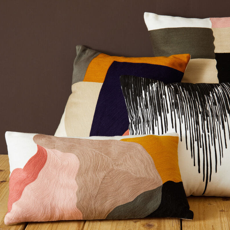Colorful patterned pillows on a wooden surface with a dark background