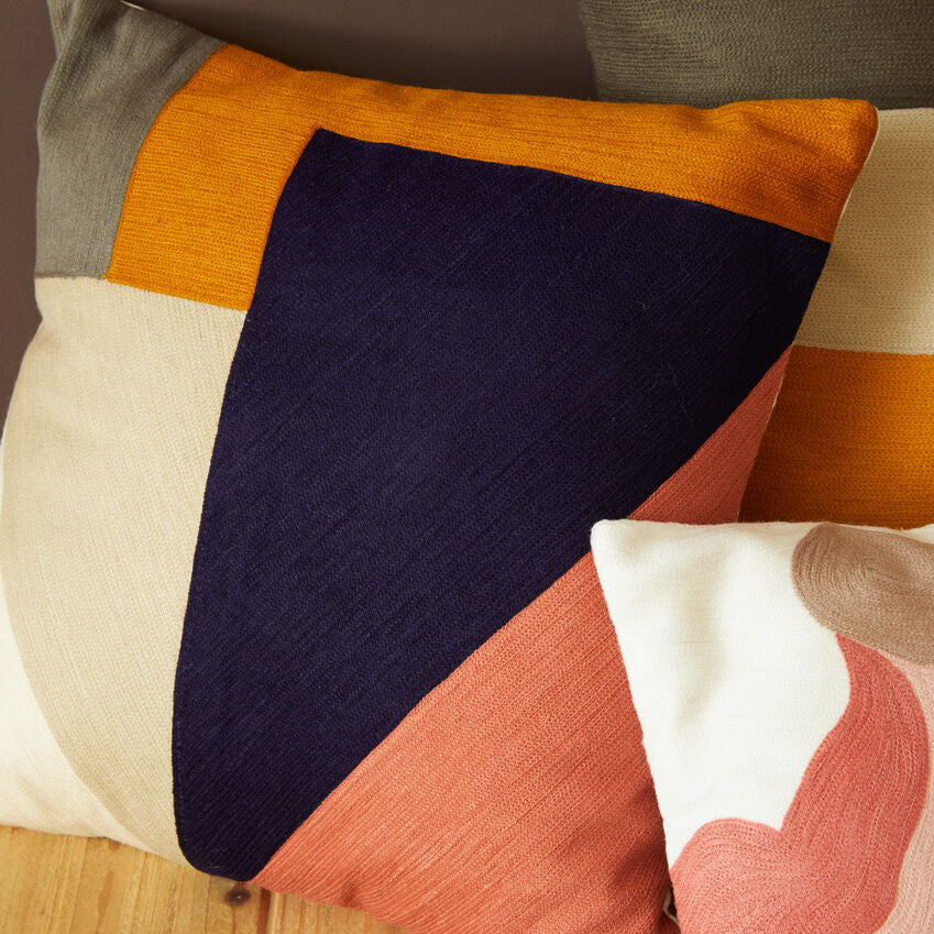 Colorful geometric-patterned cushions on a wooden surface