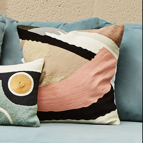 Light blue sofa with decorative pillows and a small round table with plants.